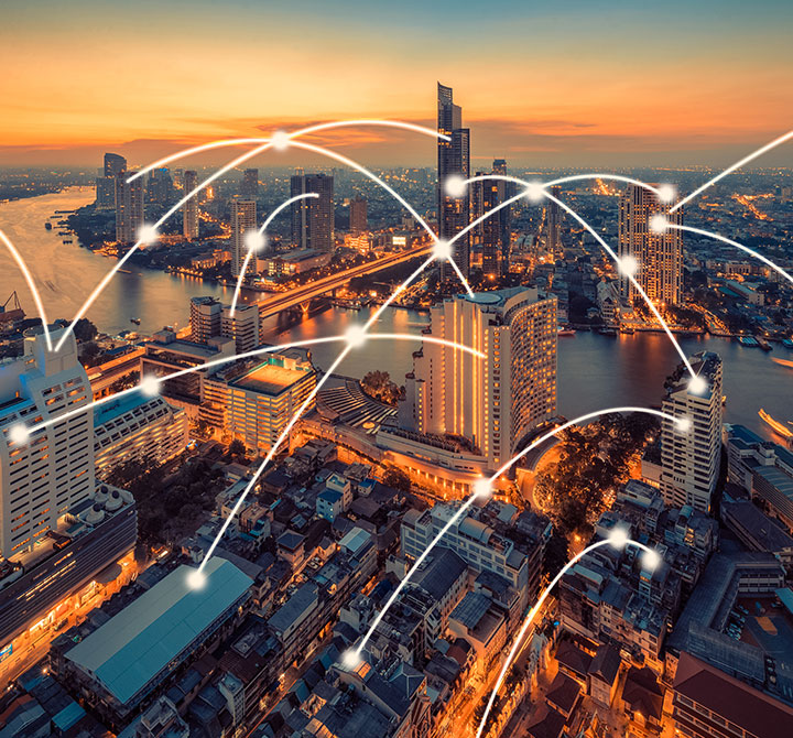 Ariel view of city in evening with IoT connectivity arches. 