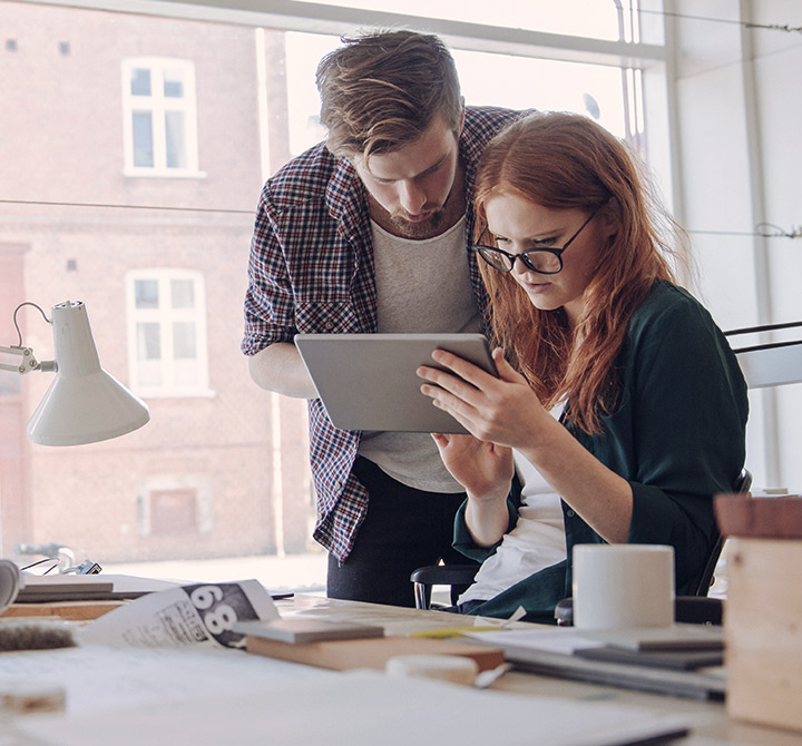Man and woman sharing a tablet in a small business setting.