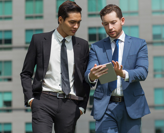 Two professional business men looking at iPad and discussing outdoor taking advantage of mobility features and add-ons  
